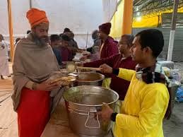 Volunteers serving food from large pots at a community gathering