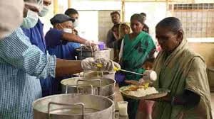 Volunteers serving fresh meals from steel containers